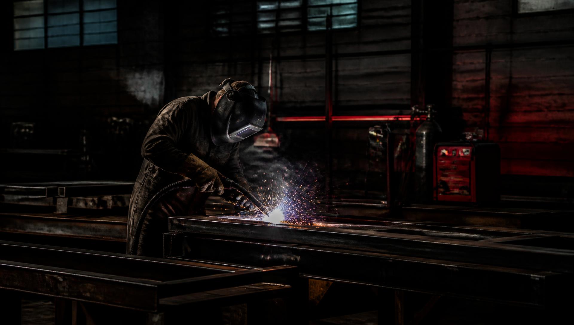 Trabajador industrial soldando estructura de acero en planta